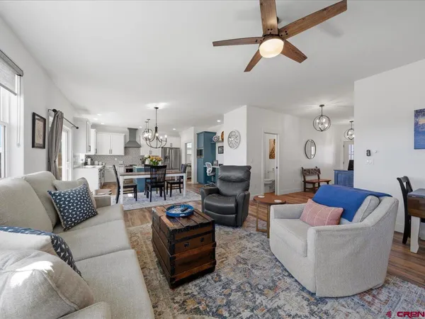 a living room with furniture kitchen view and a chandelier