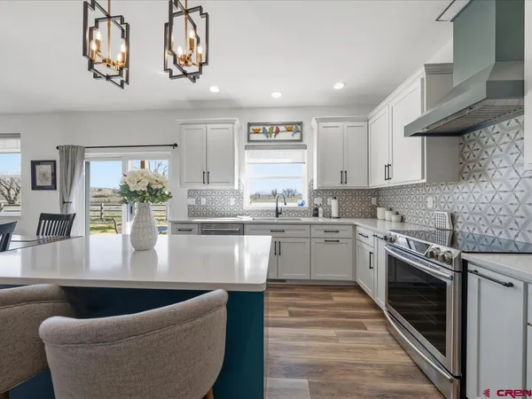 a large white kitchen with stainless steel appliances granite countertop a couch and a stove