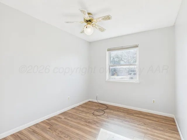 an empty room with a window and a ceiling fan