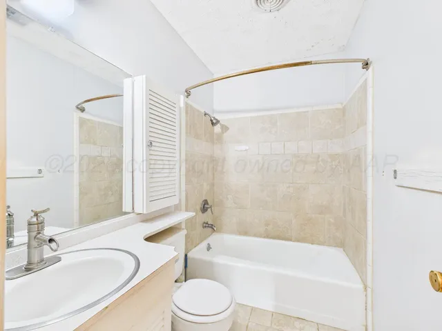 a bathroom with a bathtub shower sink vanity mirror and toilet