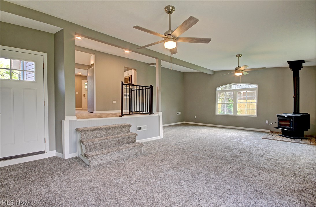 14507 Glencliffe Road Cleveland, OH 44111 - Photo 16 of 31 Unfurnished living room featuring carpet, ceiling fan, and a wood stove