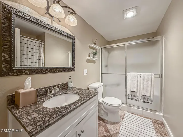 a bathroom with a granite countertop sink mirror vanity and toilet
