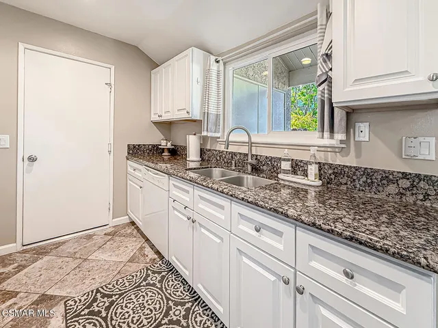 a kitchen with granite countertop white cabinets and sink