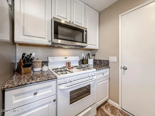 a kitchen with stainless steel appliances granite countertop white cabinets and a stove top oven