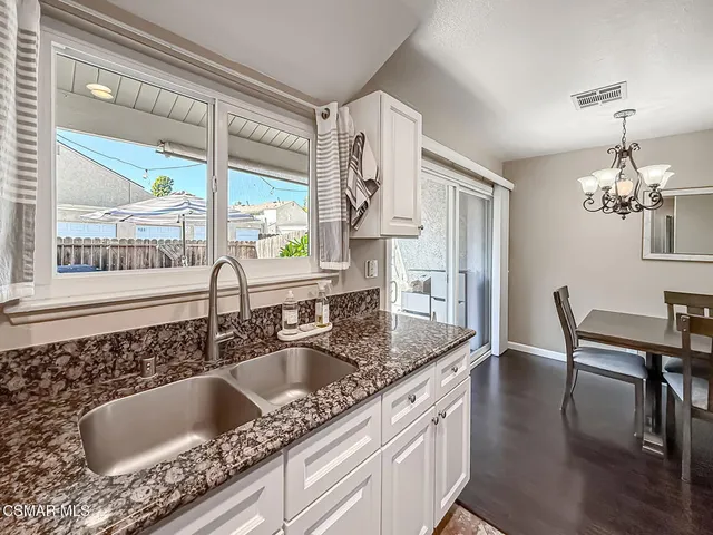 a kitchen with granite countertop a sink a counter top space and living room area