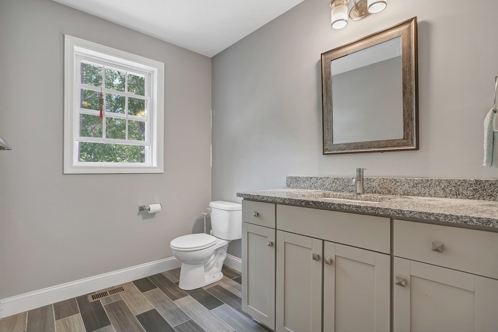 18 Castleton Avenue Randolph, MA 02368 - Photo 15 of 25 a bathroom with a granite countertop toilet a sink and a mirror