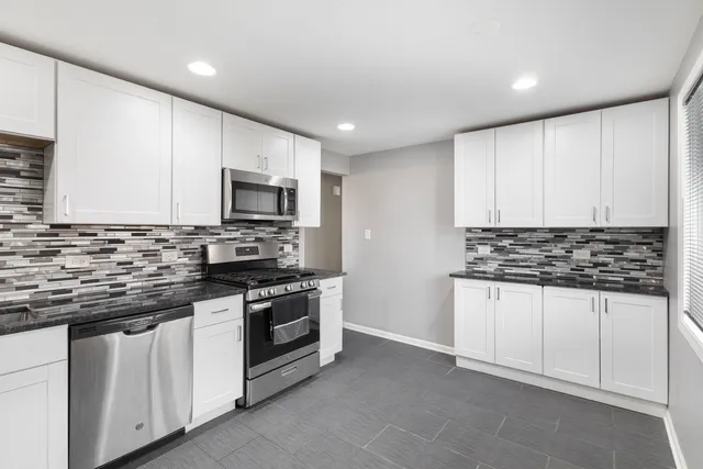 a kitchen with granite countertop white cabinets and stainless steel appliances