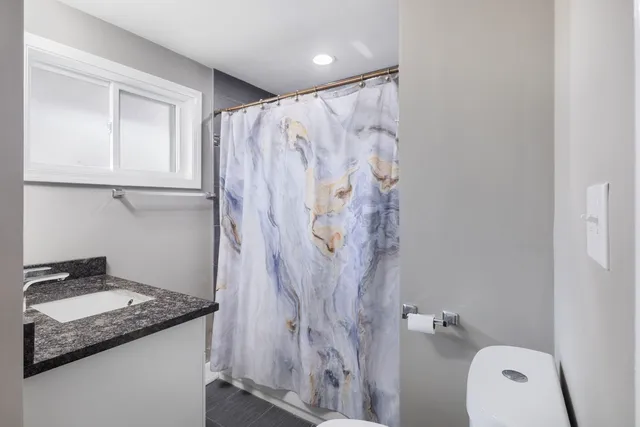 a bathroom with a granite countertop sink a toilet and a shower