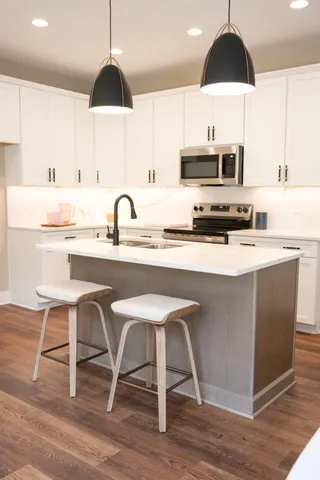 a kitchen with stainless steel appliances a dining table a sink a stove and cabinets