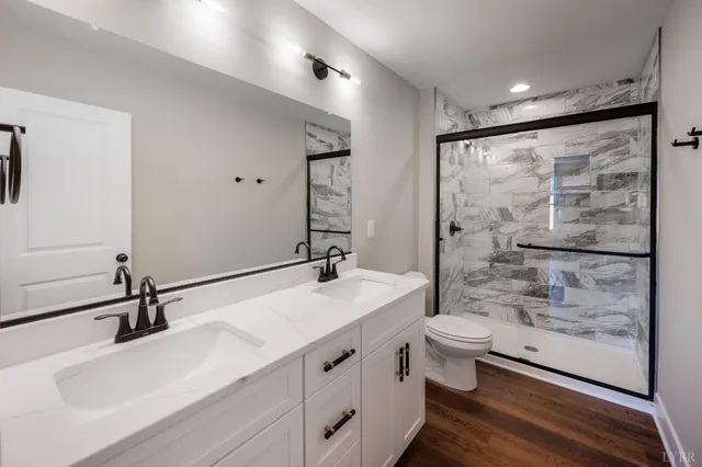 a bathroom with a double vanity sink toilet mirror and shower
