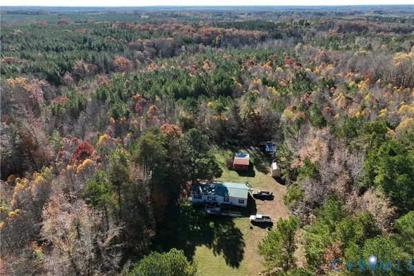 an aerial view of residential house with outdoor space and trees all around