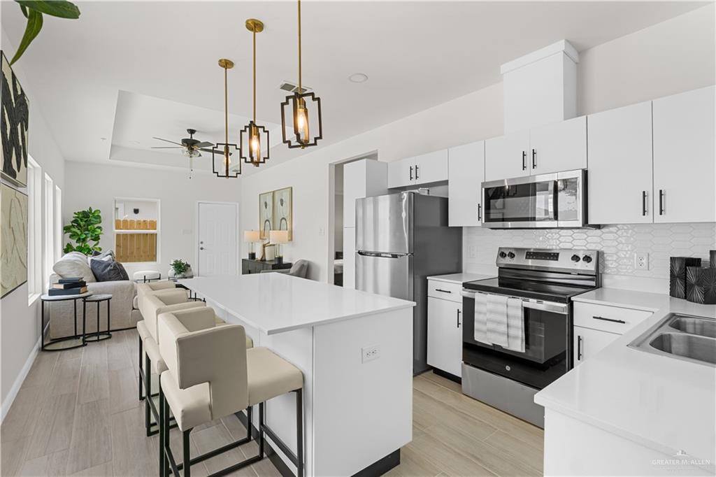 5321 Vision Street Rio Grande City, TX 78582 - Photo 6 of 34 a kitchen with stainless steel appliances granite countertop a stove a refrigerator a kitchen island a dining table and chairs with wooden floor