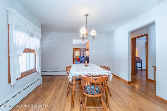 a dining room with wooden floor a chandelier a wooden table and chairs