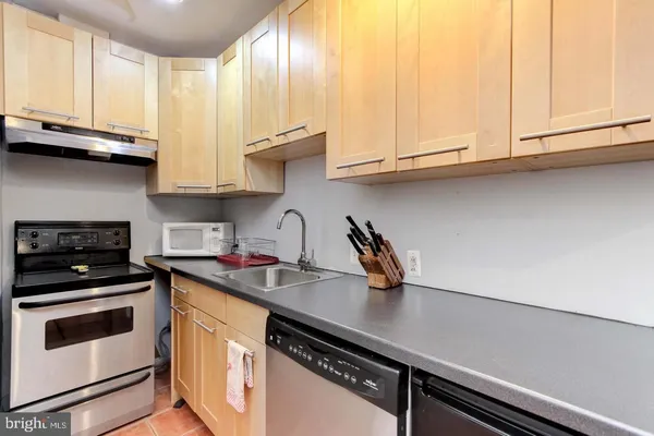 a kitchen with stainless steel appliances granite countertop a sink a stove and white cabinets