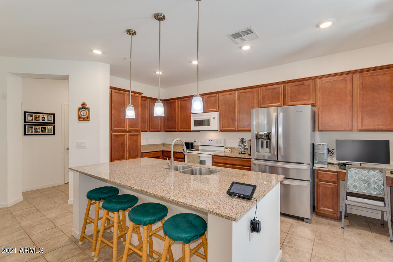 3900 East Baseline Road, Unit 135 Phoenix, AZ 85042 - Photo 6 of 19 a kitchen with stainless steel appliances granite countertop a sink a stove a refrigerator a microwave oven with a dining table and chairs
