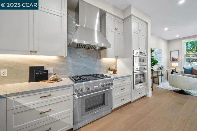 a kitchen with stainless steel appliances a stove and white cabinets