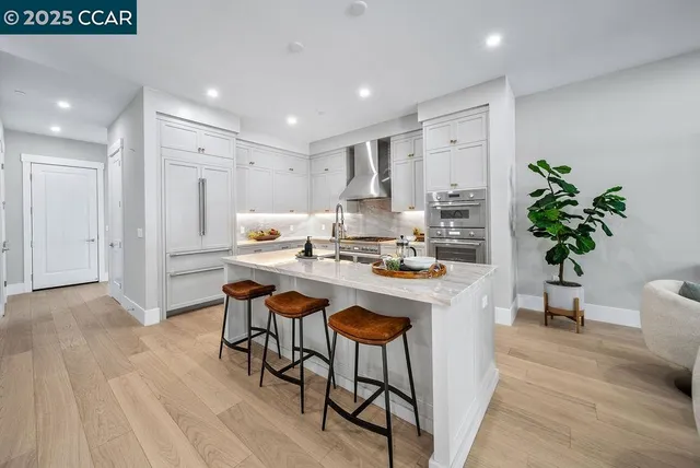 a room with stainless steel appliances kitchen island a table and chairs in it