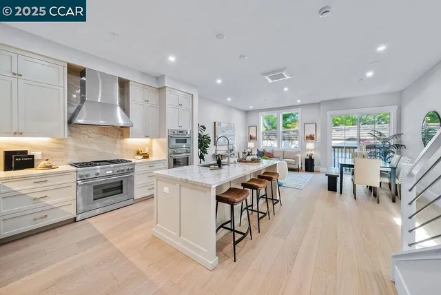 a kitchen with stainless steel appliances kitchen island granite countertop a stove a sink a refrigerator and white cabinets