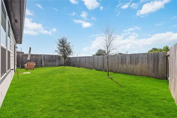 a view of a backyard with grass & fence