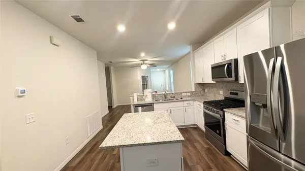 a kitchen with stainless steel appliances granite countertop a refrigerator a stove microwave and sink