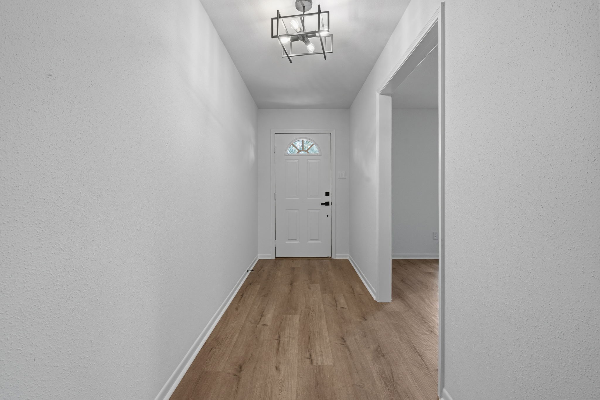 210 Ridgemont Drive Alvin, TX 77511 - Photo 3 of 27 This photo shows a bright, welcoming entryway with light-colored wood flooring, white walls, and a modern light fixture. The front door features a window, allowing natural light to brighten the space.