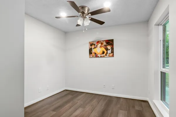 an empty room with a window and ceiling fan