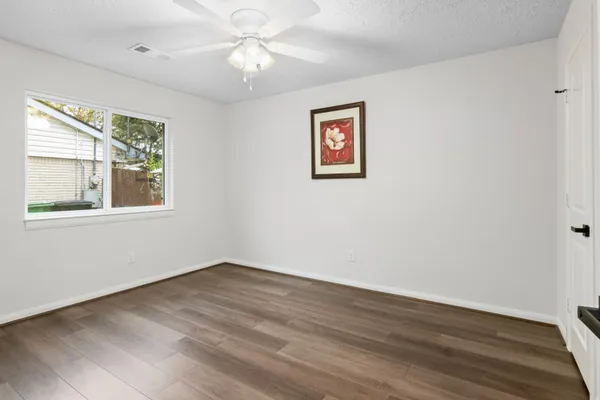 a view of an empty room with wooden floor and a window