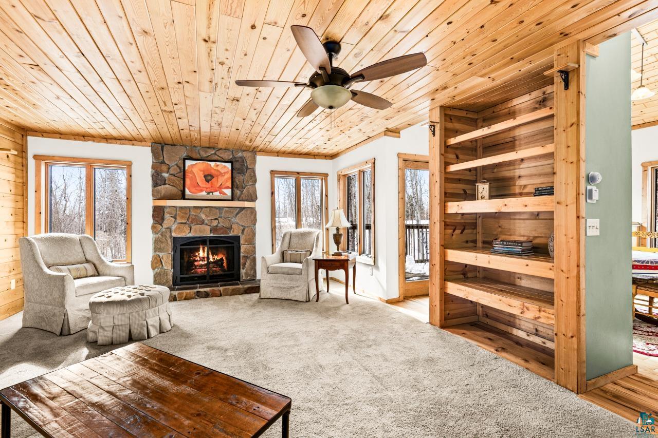 67 Snowshoe Trail Tofte, MN 55615 - Photo 12 of 42 Living area with a fireplace, light colored carpet, wooden ceiling, ceiling fan, and wood walls