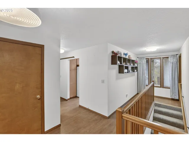 a view of a hallway with wooden floor and staircase
