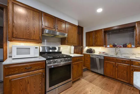 a kitchen with stainless steel appliances granite countertop wooden cabinets stove top oven and sink