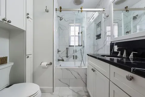 a bathroom with a granite countertop sink a toilet a mirror and shower