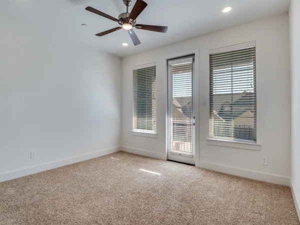 an empty room with chandelier fan and windows