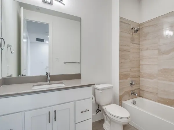 a bathroom with a granite countertop toilet a sink a mirror a shower and a bathtub