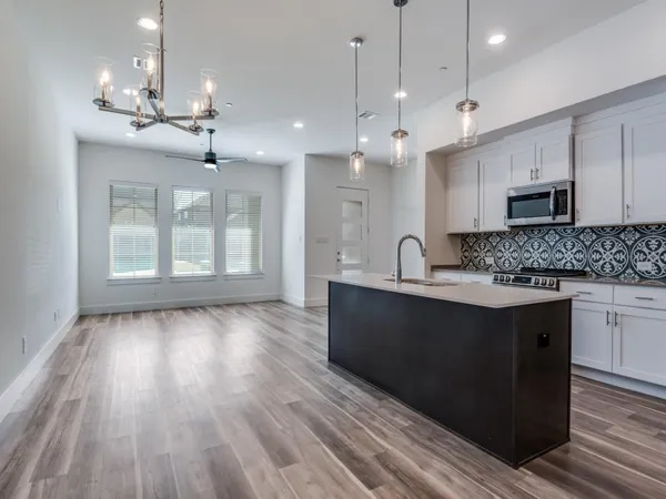 a large kitchen with granite countertop a large counter top space a sink stainless steel appliances and cabinets