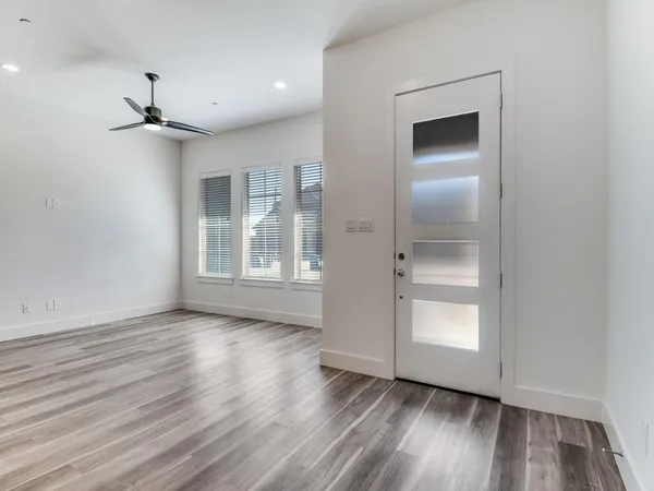 a view of an empty room with a window and wooden floor