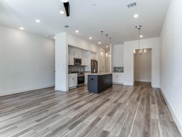 a large kitchen with stainless steel appliances kitchen island a large counter top and a refrigerator