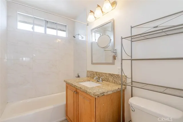 a bathroom with a granite countertop sink mirror vanity and toilet