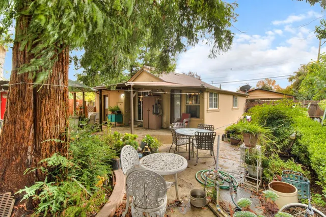 a view of a patio with table and chairs potted plants and large tree