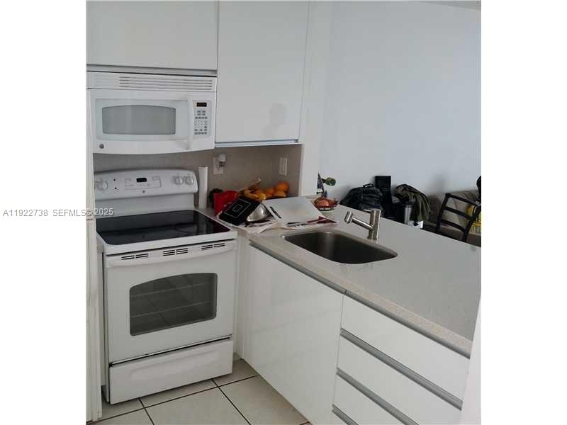 1441 Lincoln Road, Unit 308 Miami Beach, FL 33139 - Photo 10 of 10 a kitchen with white cabinets and white appliances