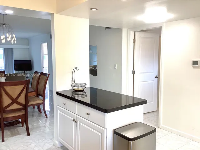 a kitchen with granite countertop white cabinets and chairs