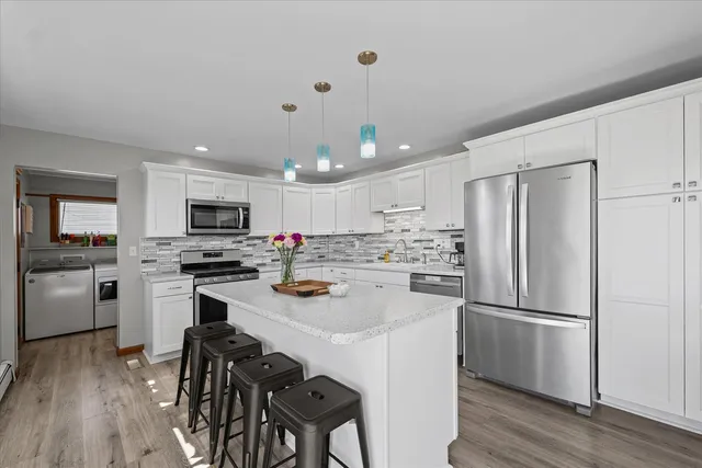 a kitchen with kitchen island white cabinets stainless steel appliances and wooden floor