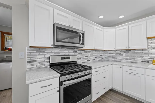 a kitchen with granite countertop white cabinets white stainless steel appliances and a sink