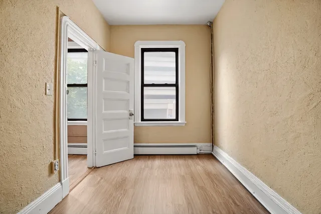 an empty room with wooden floor closet and windows