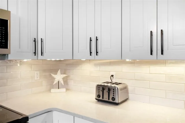 a kitchen with stainless steel appliances a dining table chairs refrigerator and cabinets