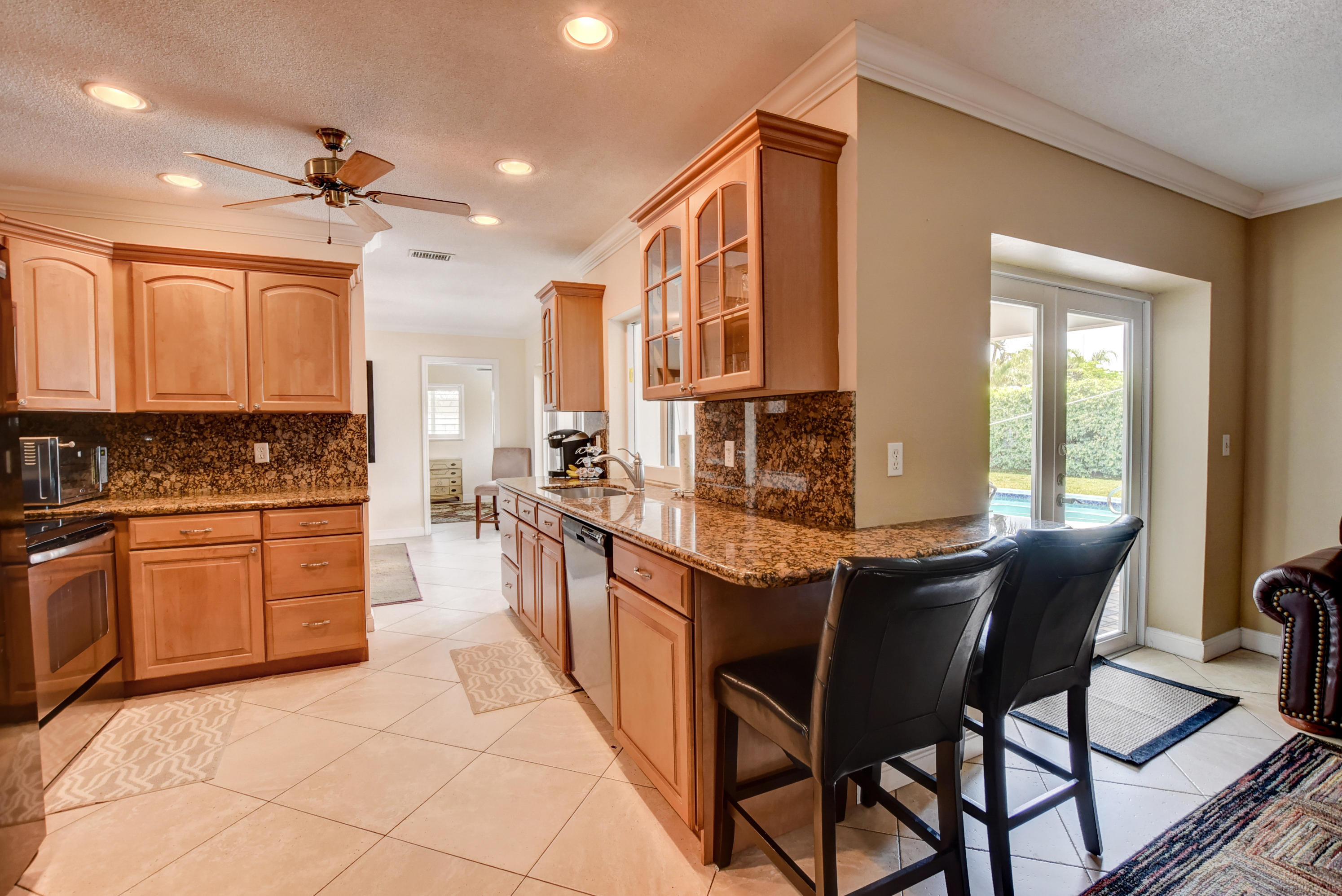 1366 Southwest 13th Place Boca Raton, FL 33486 - Photo 13 of 35 a kitchen with stainless steel appliances granite countertop a stove a sink dishwasher and a refrigerator with wooden cabinets