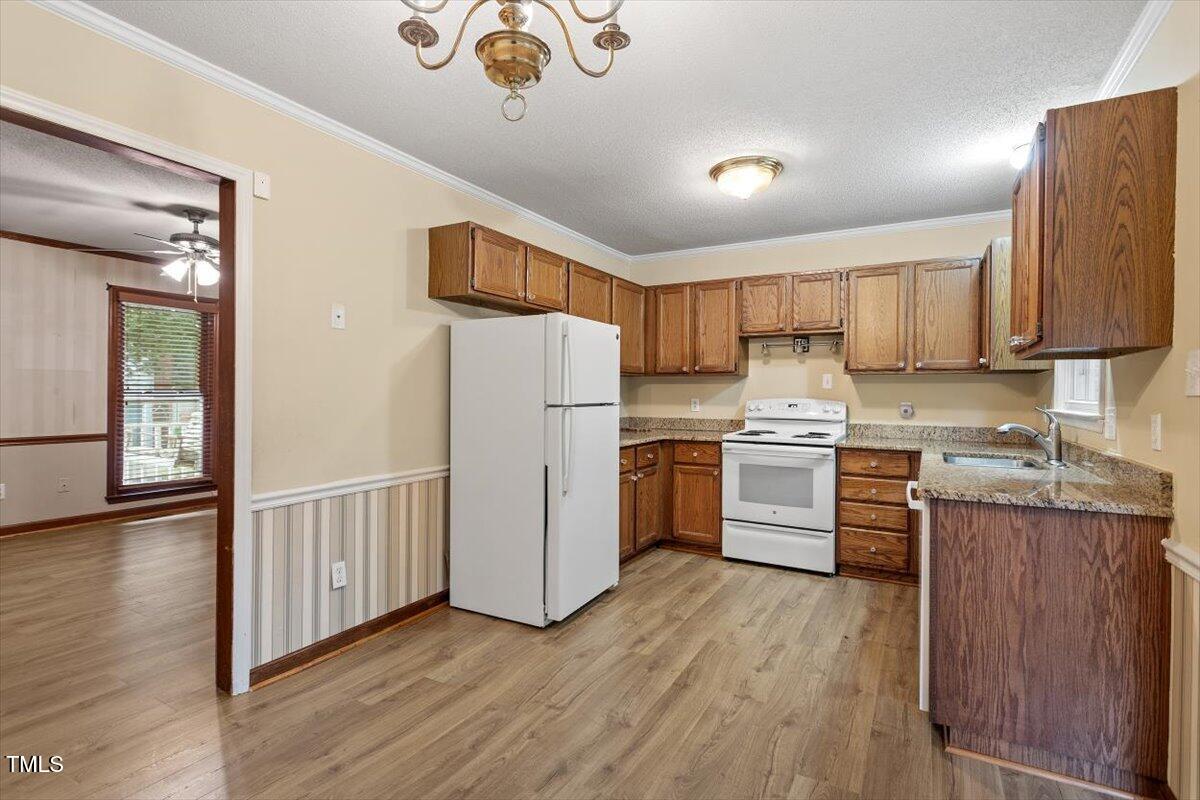 4616 Draper Road Raleigh, NC 27616 - Photo 10 of 34 a kitchen with granite countertop a refrigerator a sink dishwasher and a stove with wooden floor