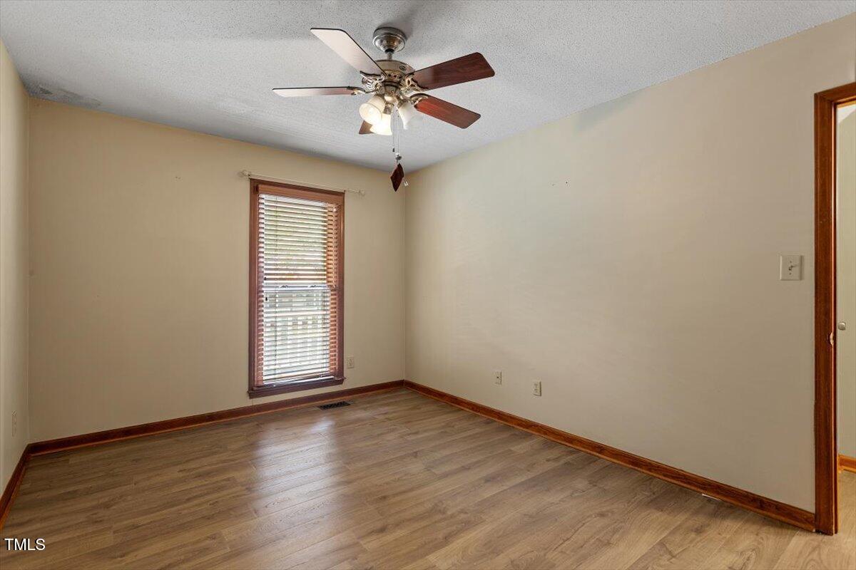 4616 Draper Road Raleigh, NC 27616 - Photo 15 of 34 an empty room with wooden floor chandelier fan and windows