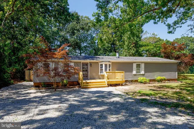 a front view of house with yard and trees in the background
