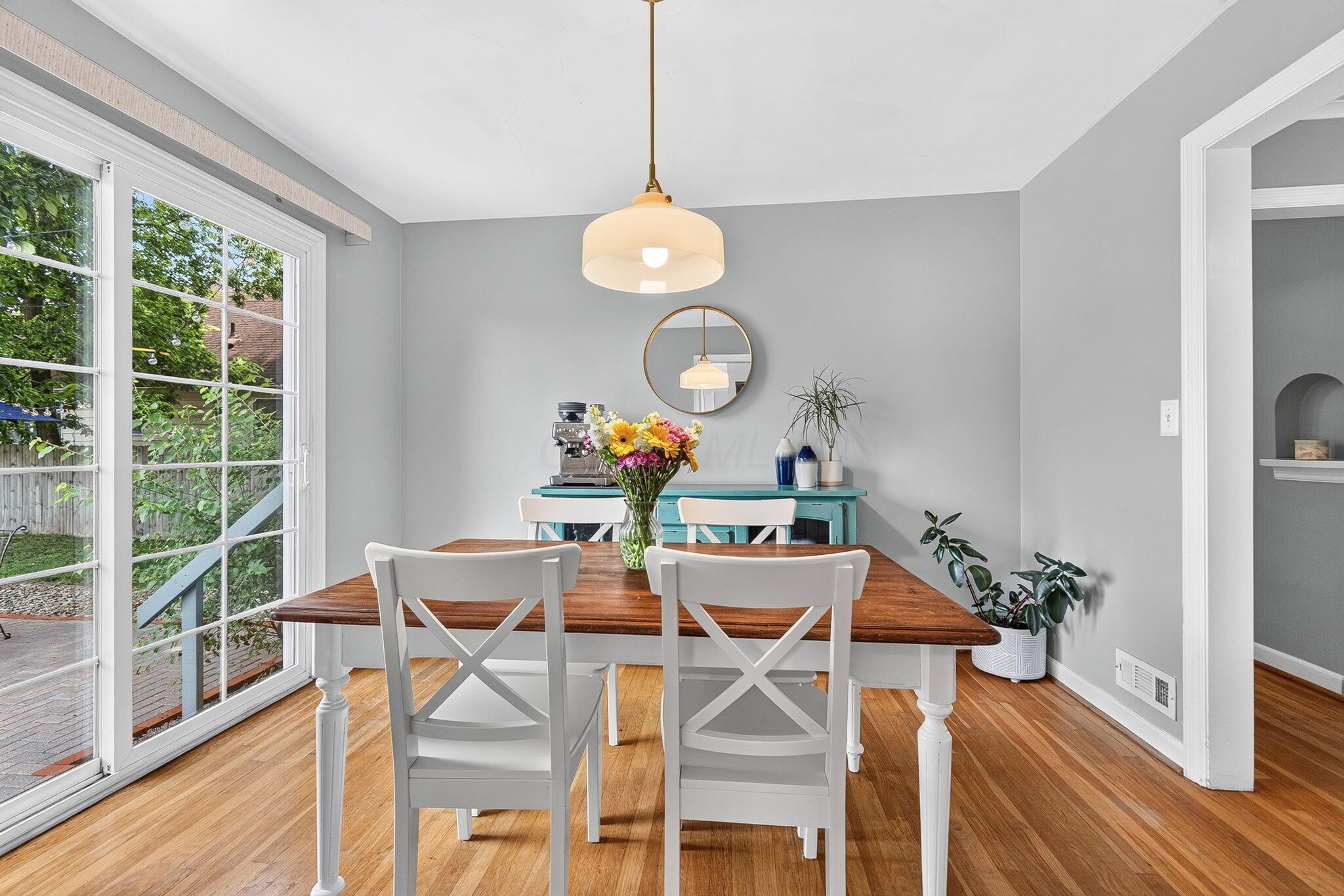 492 Wetmore Road Columbus, OH 43214 - Photo 17 of 55 Dining area featuring wood-finish flooring, a contemporary pendant light fixture, and a large sliding glass door with a grid pattern