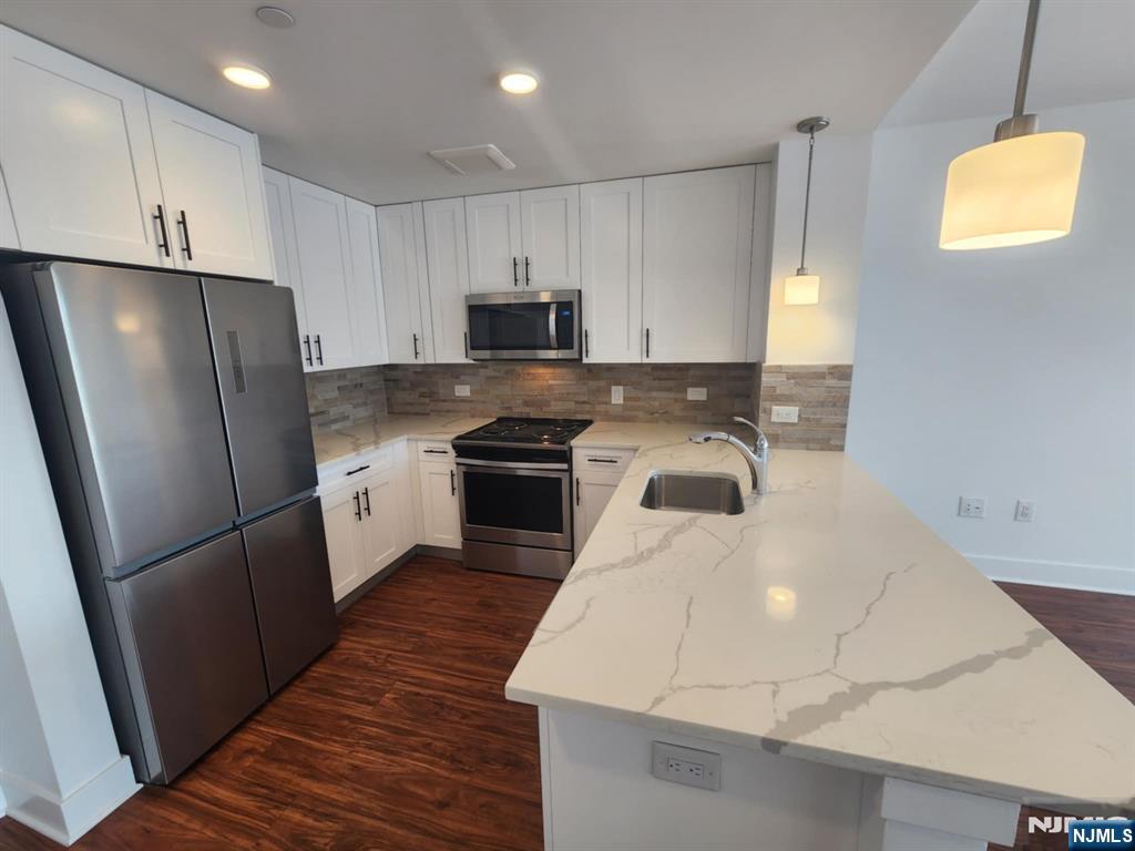 77 Ridge, Unit 108 North Arlington, NJ 07032 - Photo 5 of 24 a kitchen with stainless steel appliances a refrigerator stove microwave and sink